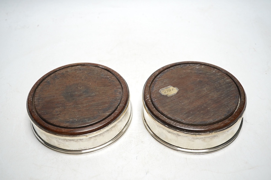 A pair of 19th century Continental white metal wine coasters, inset with turned mahogany bases, 12.5cm diameter. Condition - fair